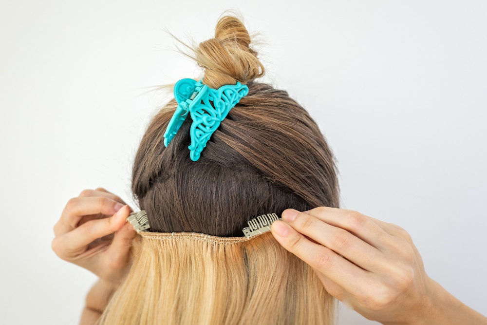 Woman removing hair extensions at home using proper techniques.