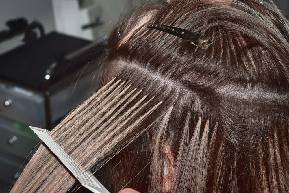 Woman removing hair extensions at home using proper techniques.