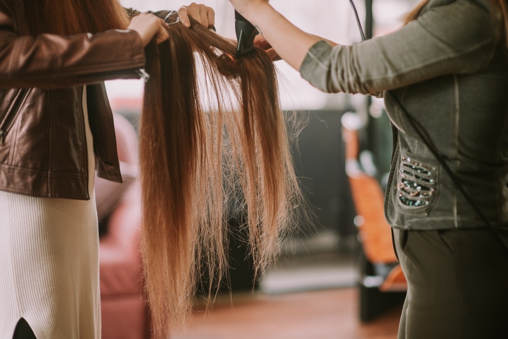 Hands braiding in hair extensions for a natural, seamless look.