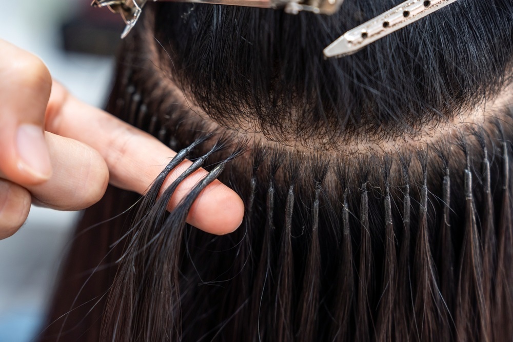 Woman removing clip on hair extensions before bedtime for healthy hair care.