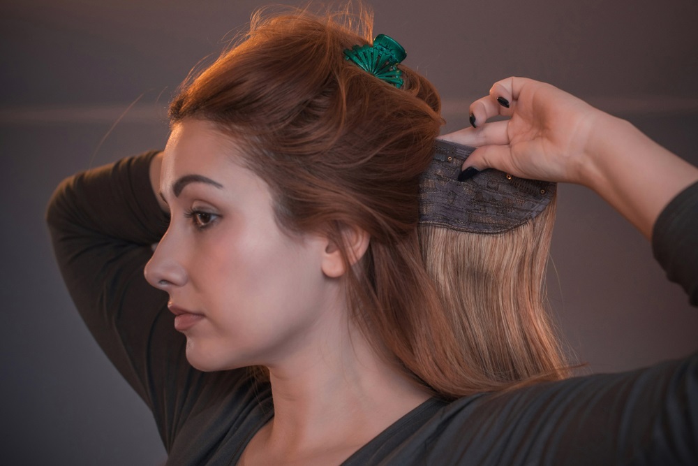 Woman removing clip on hair extensions before bedtime for healthy hair care.